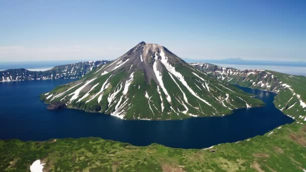 素晴らしい空の景色。緑と白の火山の円錐形、青い水、太陽の光 ストック映像