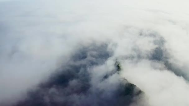 Voo aéreo sobre infinitas nuvens brancas cobrindo a costa escura com colinas verdes — Vídeo de Stock
