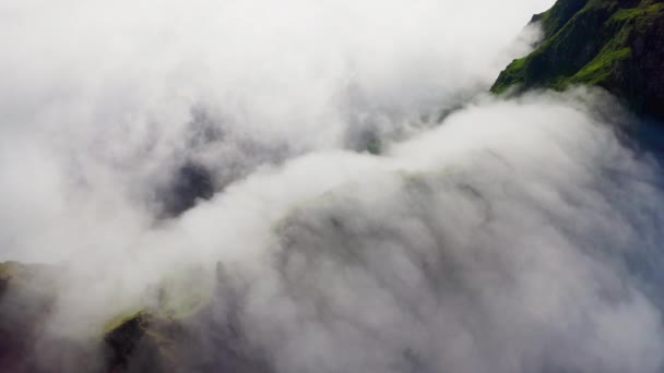 Yukarıdaki hava manzarası. Kalın beyaz bulutlar yeşil tepelerin üzerinden akıyor Telifsiz Stok Video