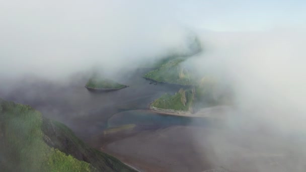 Flug durch weiße Wolken über dunklem Meer mit grünen Hügeln an einsamer Küste — Stockvideo