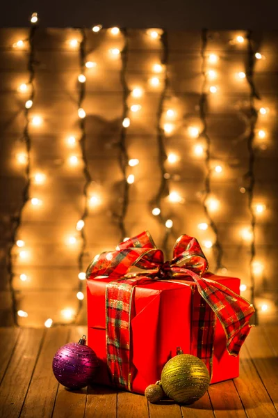 赤いリボンと背景にクリスマスライトとカラフルなクリスマスボールとクリスマスギフトボックス — ストック写真