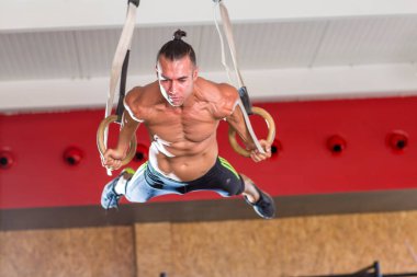 Genç ve atletik bir adam, spor salonunda egzersiz yapıyor.