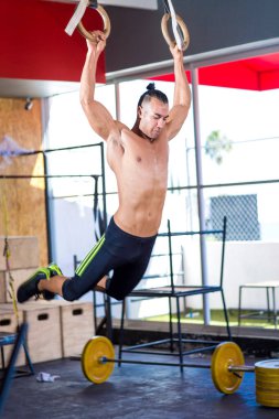 Genç ve atletik bir adam, spor salonunda egzersiz yapıyor.