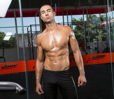 Genç ve atletik bir adam, spor salonunda egzersiz yapıyor.