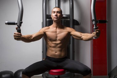 Genç ve atletik bir adam, spor salonunda egzersiz yapıyor.