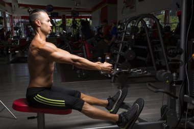 Genç ve atletik bir adam, spor salonunda egzersiz yapıyor.