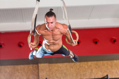 Genç ve atletik bir adam, spor salonunda egzersiz yapıyor.