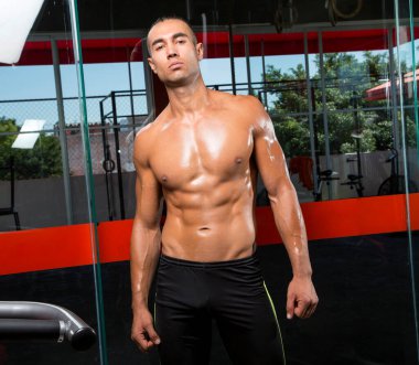 Genç ve atletik bir adam, spor salonunda egzersiz yapıyor.