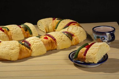 delicious rosca de reyes on wooden table, rosca de reyes ready to eat served in an artisanal plate with hot chocolate drink., delicious Mexican tradition, January 6, Three Kings Day.