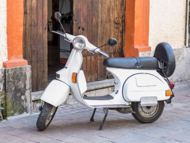 white scooter with old house in background