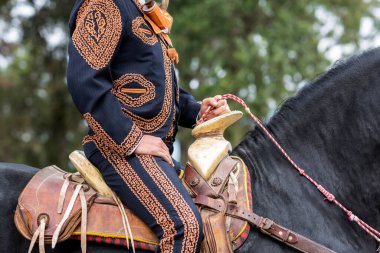 handsome mexican charro riding a beautiful black horse