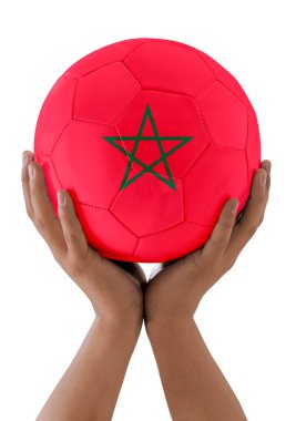 Adamın elleri, Fas takımının bayrağını taşıyan bir futbol topunu beyaz arka planda bir kupa olarak kaldırıyor..