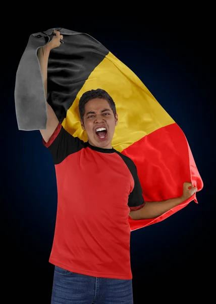 黒を背景にチームの勝利への想いを胸にベルギーとジャージーの国旗を掲げたサッカーファン — ストック写真