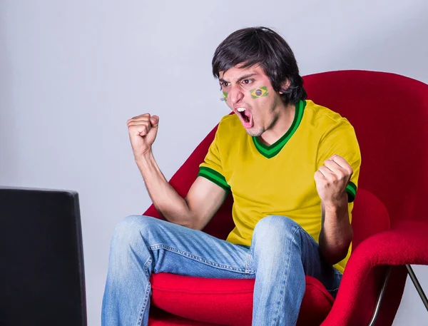 Футбольный Фанат Смотрит Телевизор Майкой Лицом Раскрашенным Флагом Бразильской Команды — стоковое фото