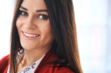 Kırmızı ceketli güzel iş kadını ofiste çalışıyor.