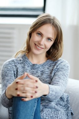 Kameraya bakarak ve gülümseyerek mutlu bir genç kadın 