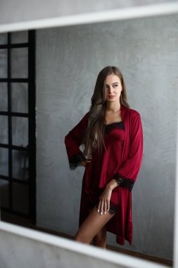 Lingerie and nightwear concept. Beautiful young woman in red nightgown locking in the mirror
