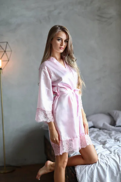 穿着粉色睡衣的性感金发女人在舒适的公寓里摆姿势 — 图库照片