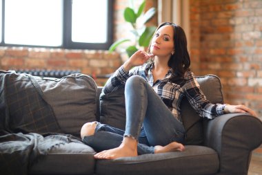 Portrait of young beautiful woman in plaid shirt reaxling at home