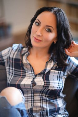 Portrait of young beautiful woman in plaid shirt reaxling at home