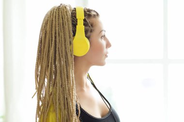 Woman with yellow dreadlocks listening music on the kitchen