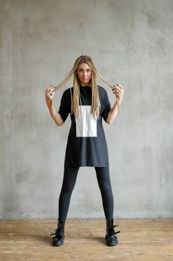 Beautiful young woman with dreadlocks posing on grey background