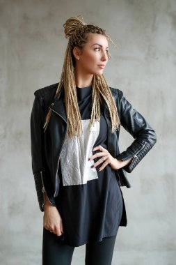 Beautiful young woman with dreadlocks posing on grey background