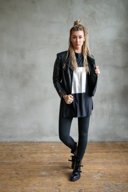 Beautiful young woman with dreadlocks posing on grey background