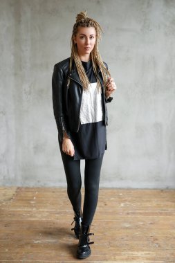 Beautiful young woman with dreadlocks posing on grey background