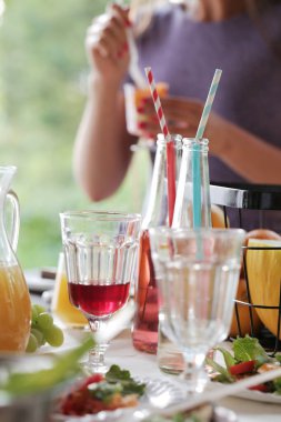 Variety of food and drinks on the table, woman drinking on background
