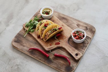 Delicious tacos on the wooden cutting board