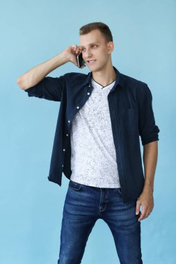 Mavi arka planda telefonu olan yakışıklı adam.