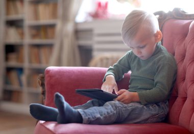 Evde tabletli genç bir çocuk var.