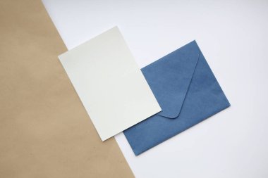 Dikey olarak, beyaz ve kahverengi arkaplan üzerinde, mavi kapalı zarf ve dikey beyaz sayfa