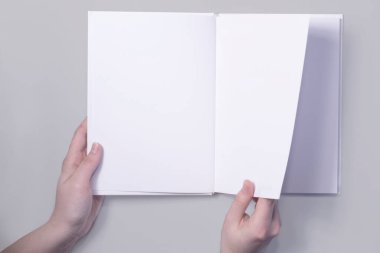 Sayfayı çeviren eli açık bir kitabın kopyası. Tasarım sunumu için uygulanabilir