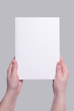 Ellerinde beyaz bir ciltli kitap kapağı var. Tasarım sunumu için uygulanabilir