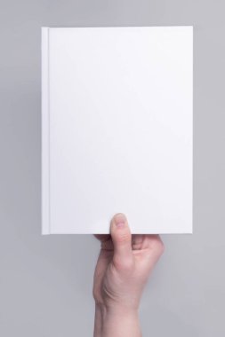 Ellerinde beyaz bir ciltli kitap kapağı var. Tasarım sunumu için uygulanabilir