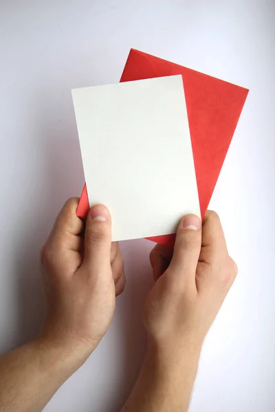 男性的手拿着白纸和红色的信封在白色的背景上 明信片的布局 — 图库照片