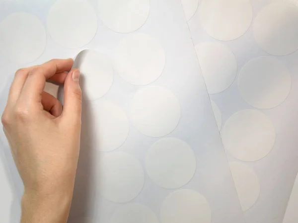一只整洁的雌性手从绘图机修剪的圆形白色贴纸上剥下 模拟贴纸 — 图库照片
