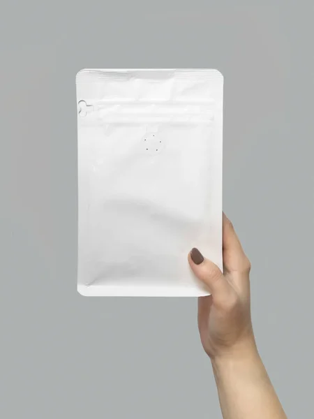 mockup of a white pack of coffee in hands on a gray background. template for design