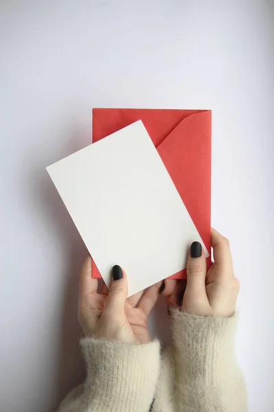 女性的手穿着毛衣 修指甲 白色的床单 红色的信封 白色的背景 明信片的布局 — 图库照片