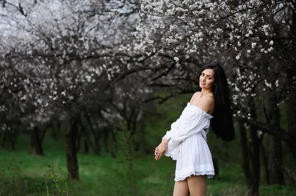 Fille dans une robe blanche sur un fond de fleurs — Photo