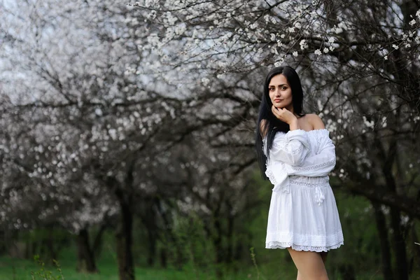 Mädchen in einem weißen Kleid auf einem Hintergrund aus Blumen — Stockfoto