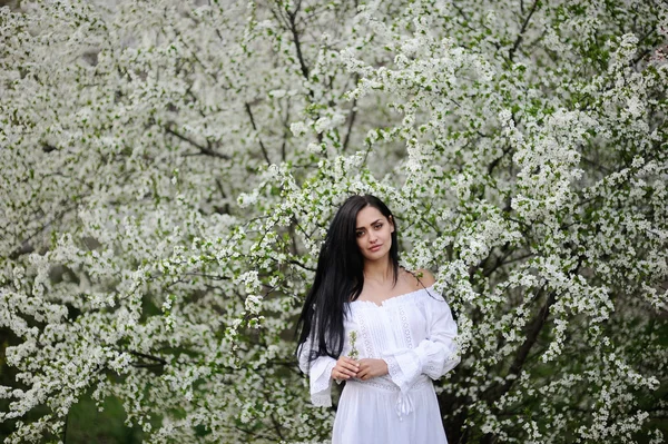 Niña en un vestido blanco sobre un fondo de flores — Foto de Stock