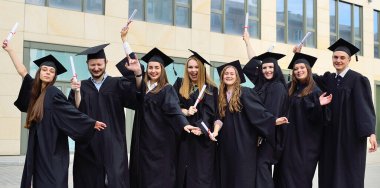 Siyahi öğrenci cübbesi ve kare şapkalı öğrenciler diploma almaktan ve eğitim sürecini tamamlamaktan memnuniyet duyuyorlar..