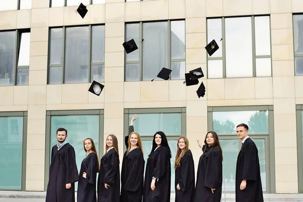 A köpenyes diákok akadémiai sapkákat dobnak fel, és boldogan kapnak felsőoktatást. — Stock Fotó