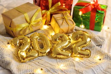 Noel hediyelerinin ve Noel ışıklarının arka planında örülmüş ekose kumaş üzerinde 2022 numara..