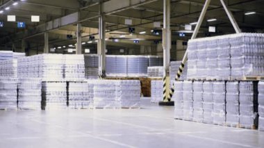 Arkaplanda bira, su ve içeceklerle dolu plastik PET şişeleri olan büyük bir endüstriyel gıda deposu var..