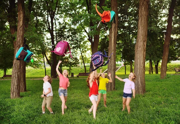 Grupo de crianças da escola se alegrar no início das férias de verão, jogar as mochilas da escola e rir. — Fotografia de Stock