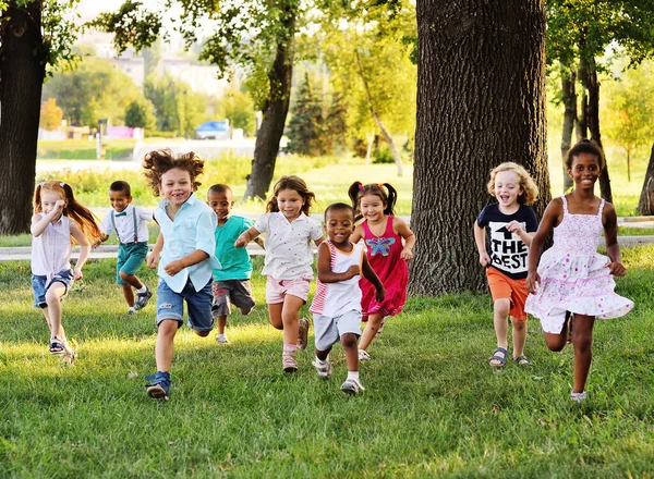 Sekelompok anak TK berlari di atas rumput di taman. — Stok Foto